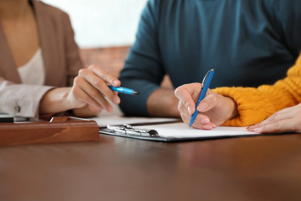 couple signant des papiers légaux avec une avocate